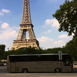 Coast to Coast Travel coach in France with a view of the Eiffel Tower in the background